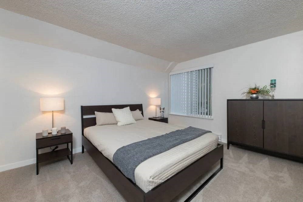 A bedroom with a bed, nightstands, and a cabinet.