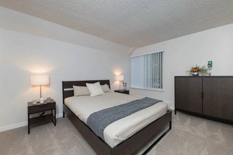A bedroom with a bed, nightstands, and a cabinet.
