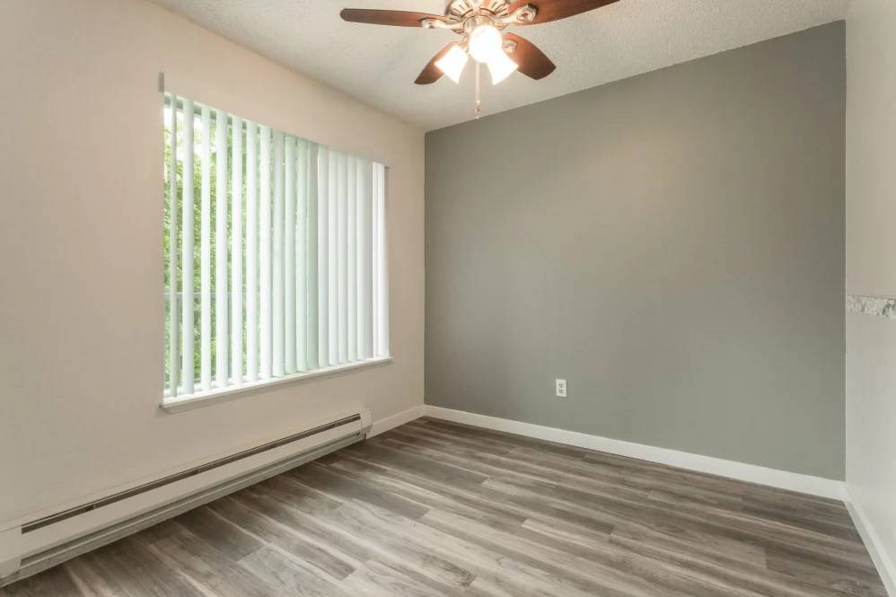 A room with a ceiling fan and a window with blinds.