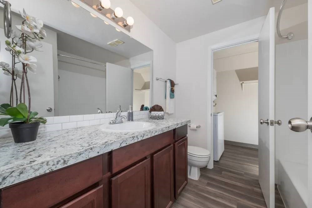 A bathroom with a marble countertop and a toilet in the background.