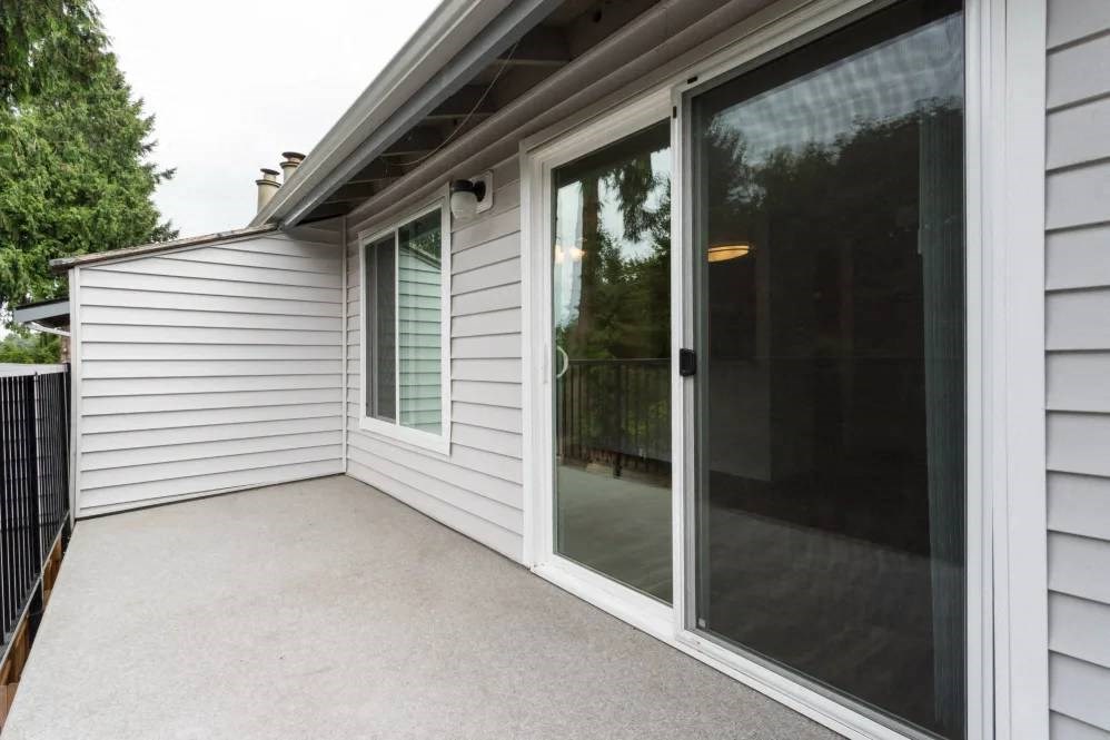 A patio area with a sliding glass door and a white wall.