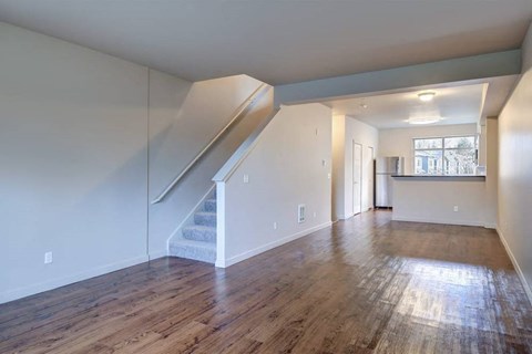 A spacious room with wooden floors and a staircase.