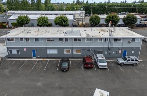 A grey building with a parking lot in front of it.