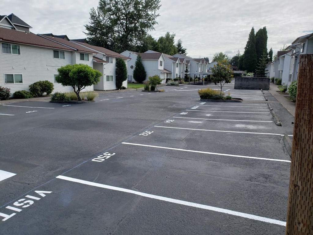 an empty parking lot with houses on the side of it