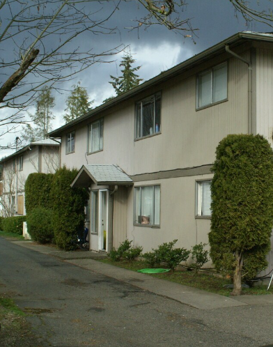 A residential building with a grey roof and beige siding.