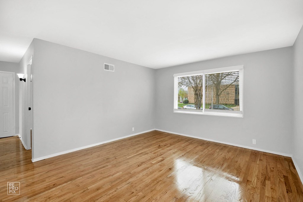 a bedroom with hardwood floors and a large window