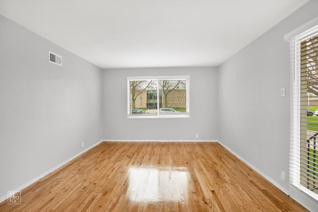 a bedroom with a large window and hardwood floors