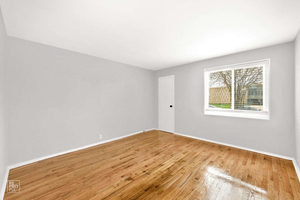 a bedroom with hardwood floors and a large window