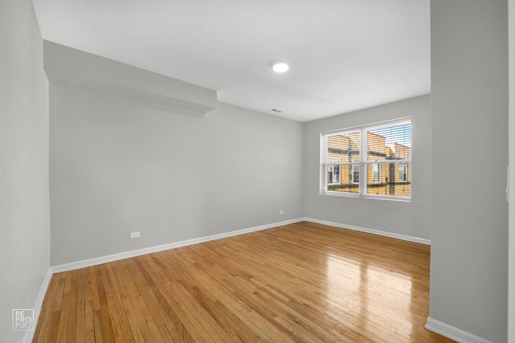 a bedroom with grey walls and hardwood floors