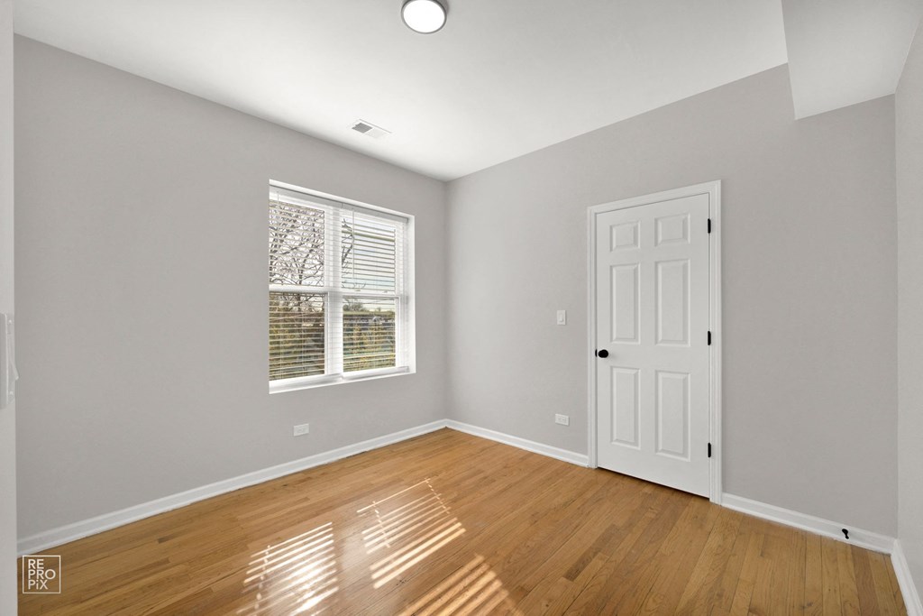 a bedroom with gray walls and hardwood floors