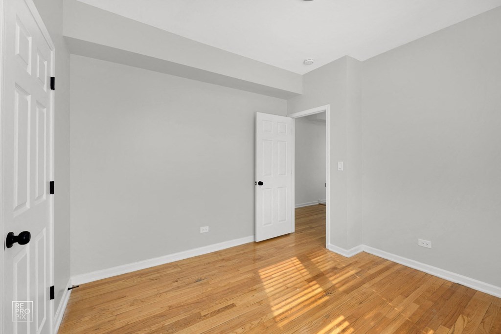 a bedroom with grey walls and hardwood floors