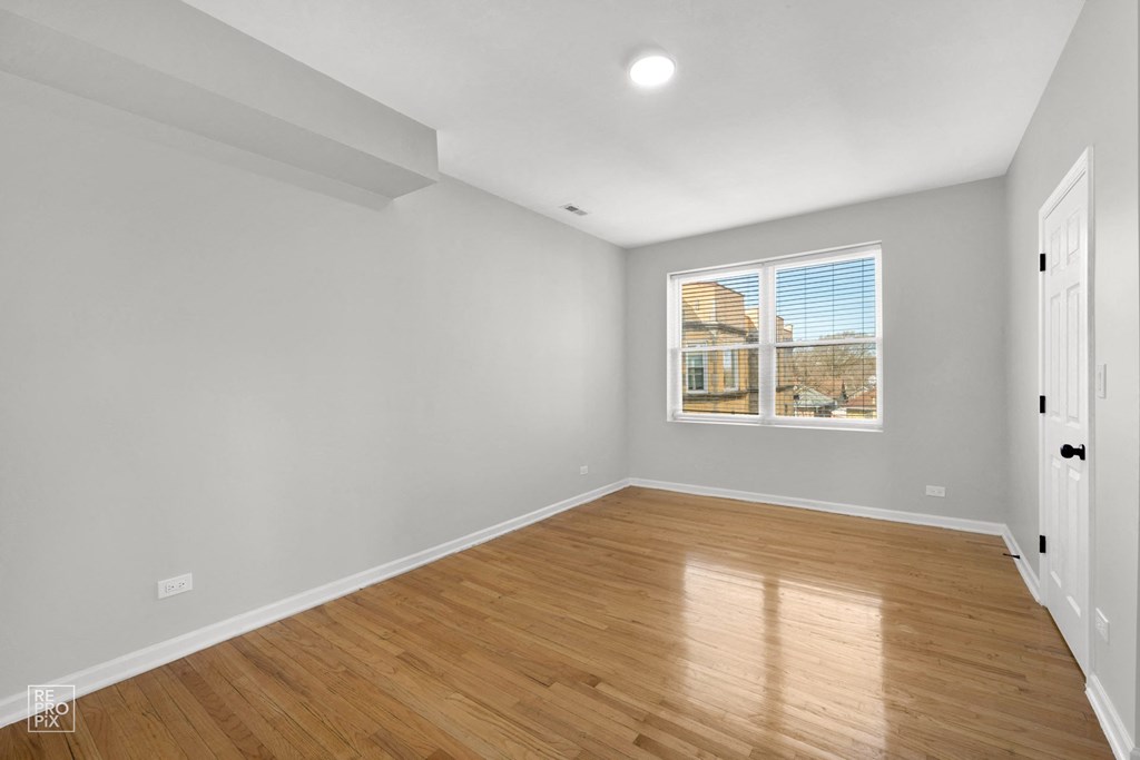 a bedroom with grey walls and hardwood floors