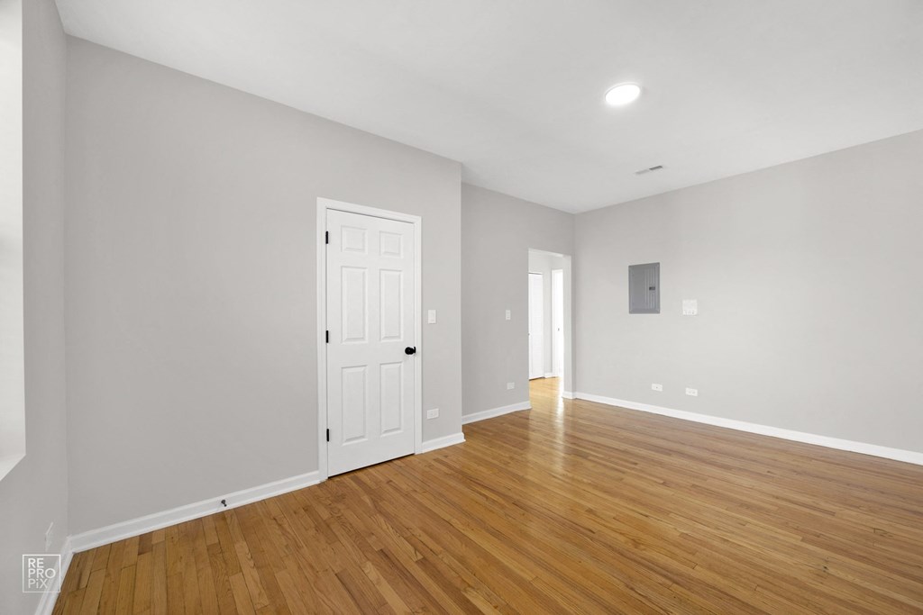 a bedroom with hardwood floors and grey walls