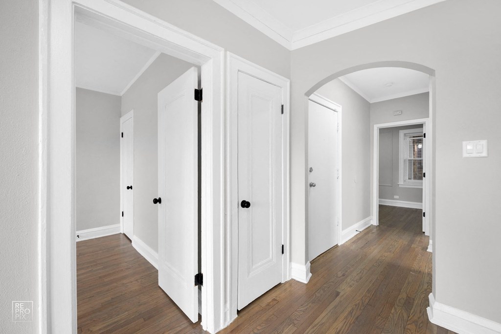 a bedroom with white walls and hardwood floors