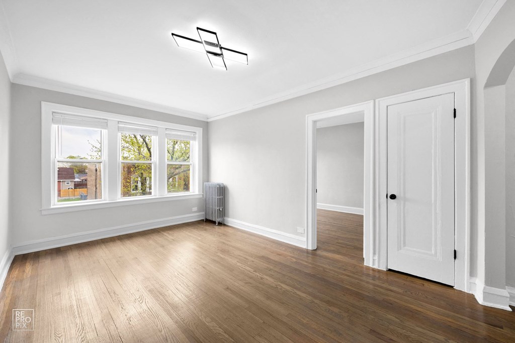 a bedroom with hardwood floors and white walls