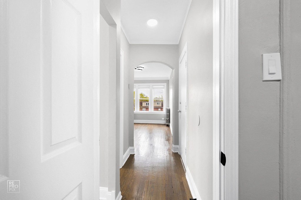 a hallway with white walls and hardwood floors