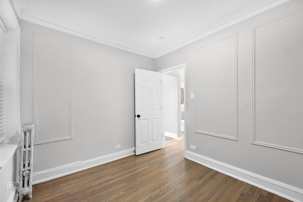 a bedroom with white walls and hardwood floors