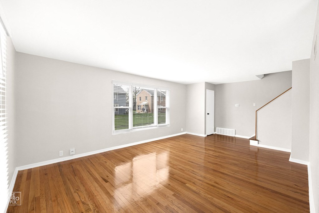 a bedroom with hardwood floors and a large window