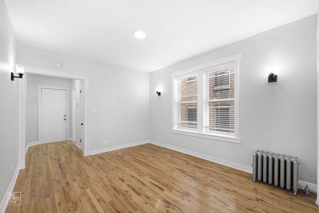 a bedroom with a hardwood floor and two windows
