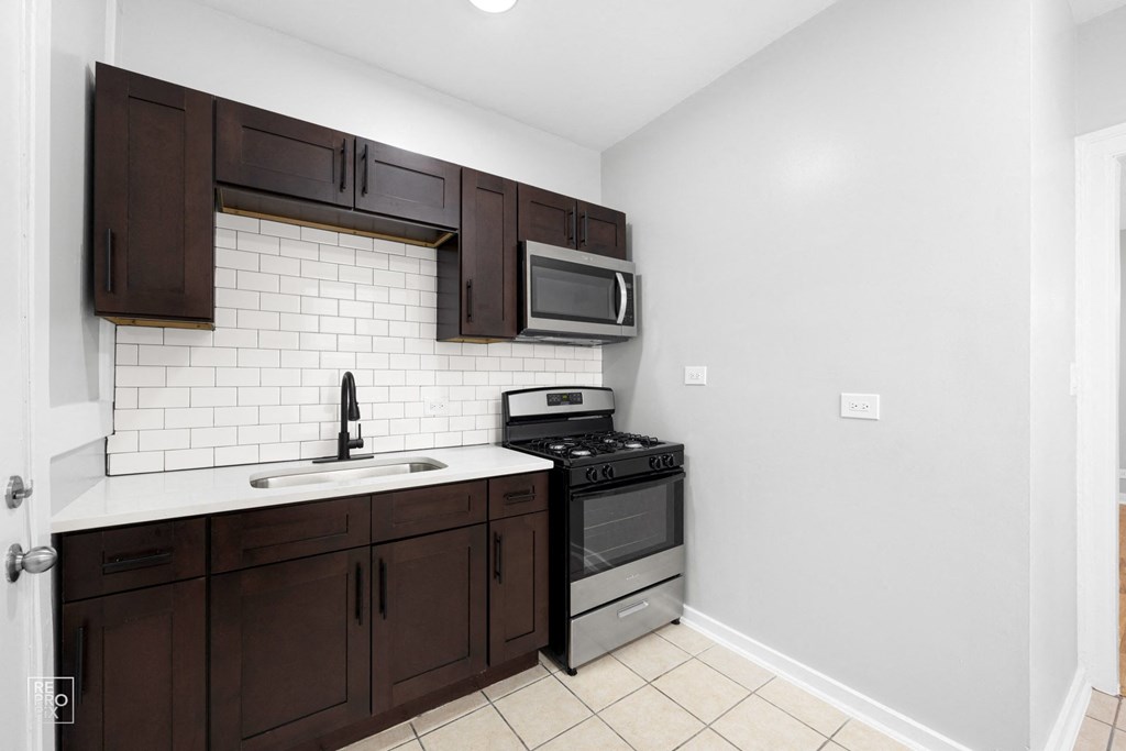 a kitchen with dark cabinets and white countertops