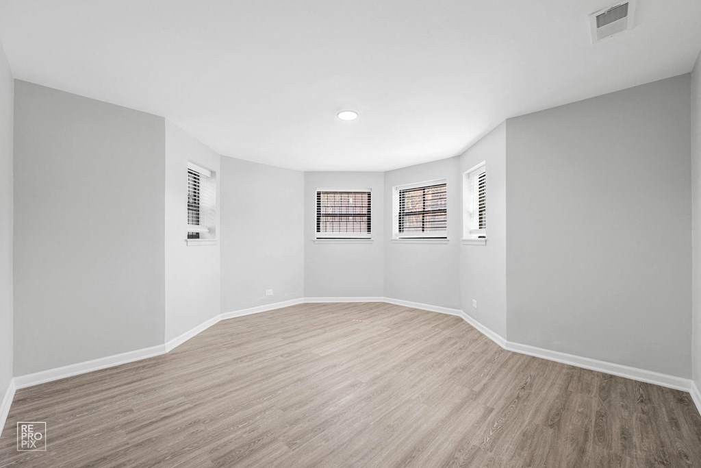 a bedroom with grey walls and a hardwood floor