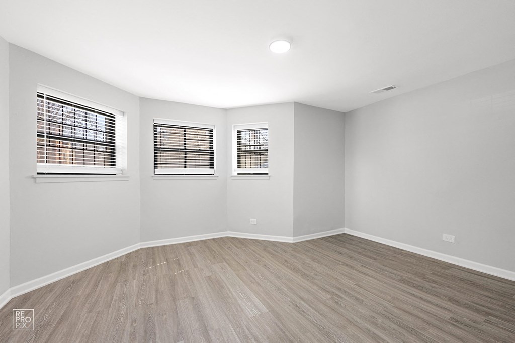 a bedroom with gray walls and hardwood floors