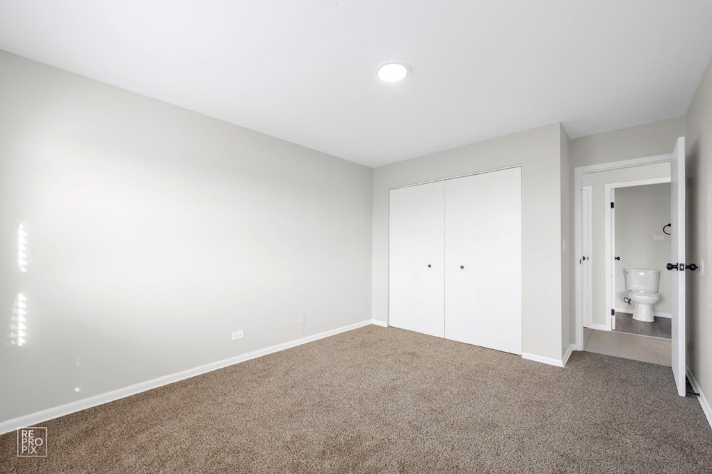 a bedroom with white walls and a beige carpet