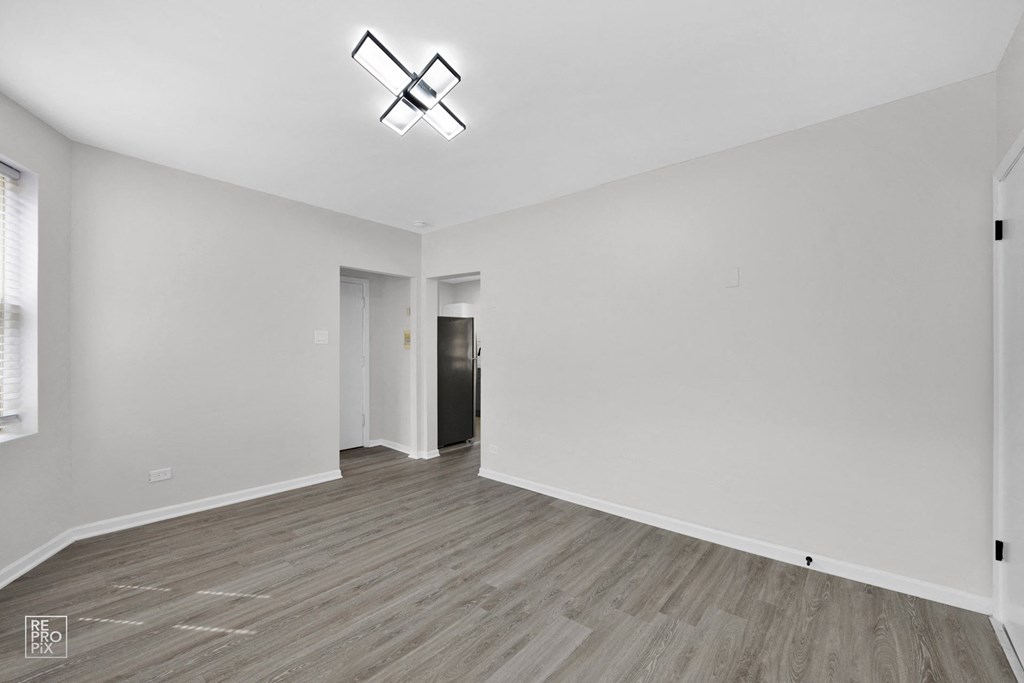 a bedroom with white walls and hardwood floors