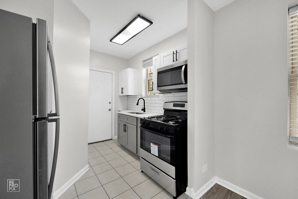 a kitchen with white tile flooring and stainless steel appliances