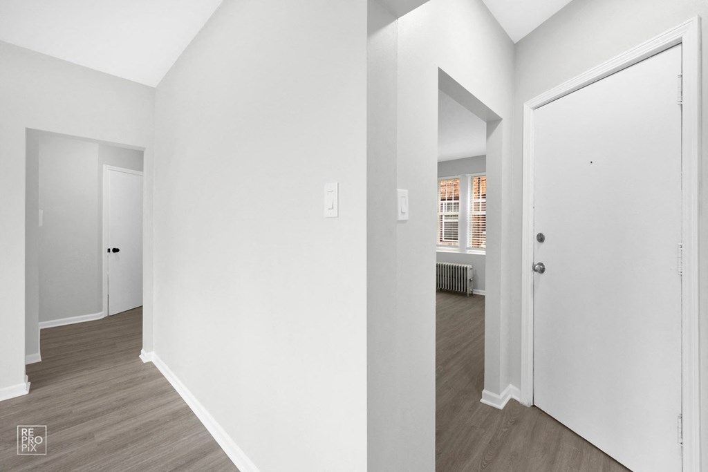 a bedroom with white walls and hardwood floors