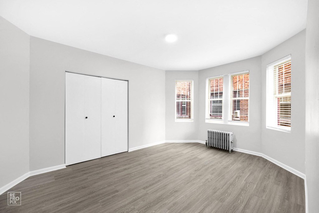 a bedroom with hardwood floors and white walls