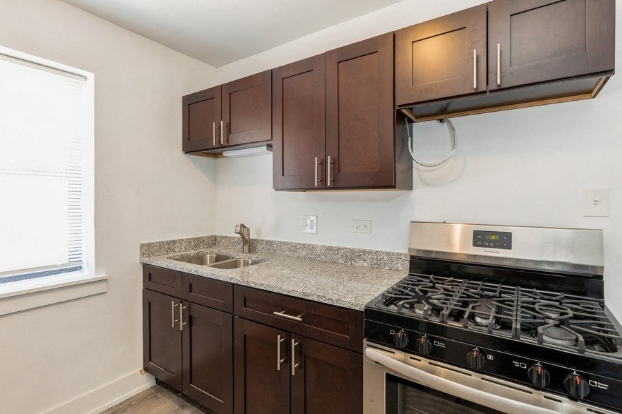 an empty kitchen with a stove and sink and wooden cabinets