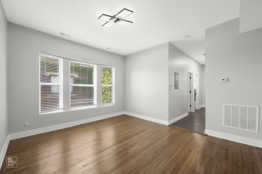 an empty living room with wood floors and a large window