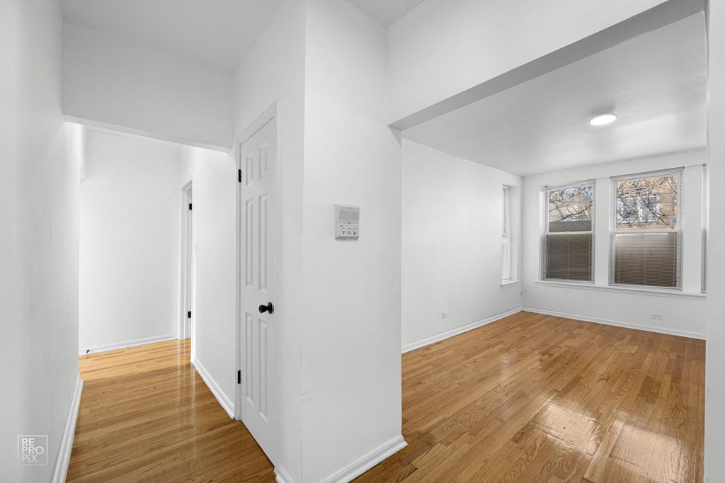 a living room with white walls and wood floors and a white door