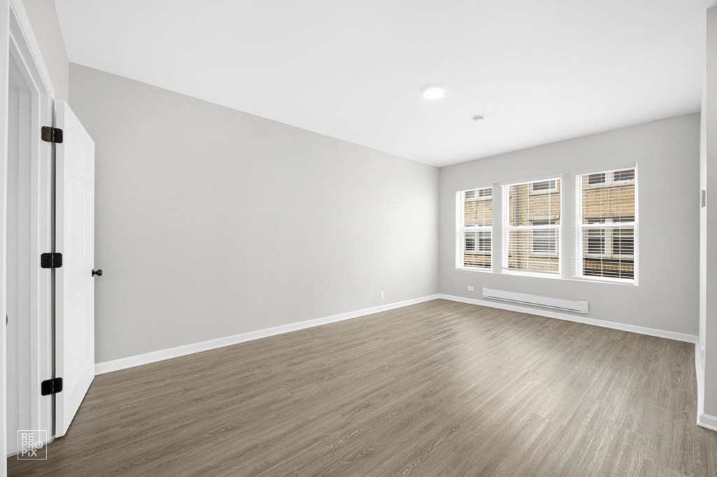 a bedroom with gray walls and hardwood floors