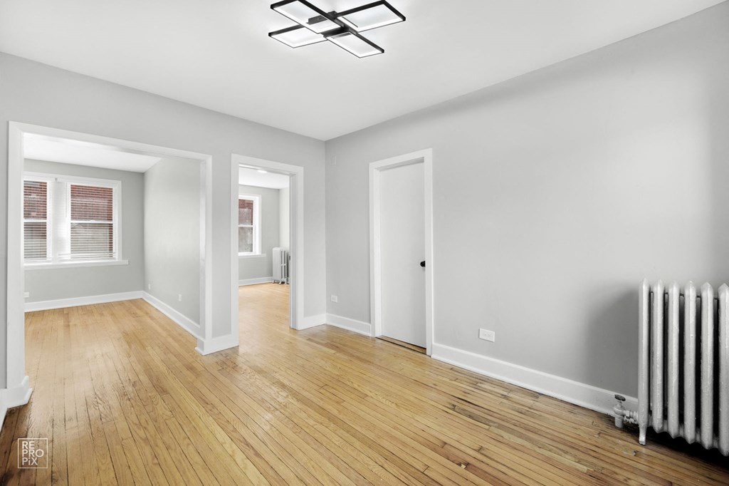 a bedroom with grey walls and hardwood floors