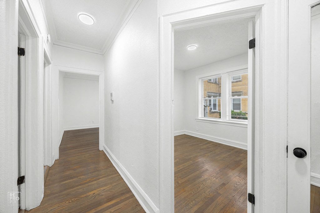a renovated living room and hallway with white walls and wood floors