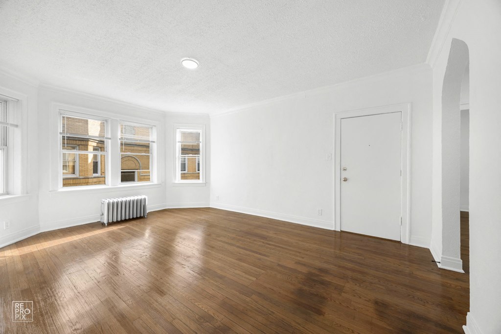 an empty living room with wood floors and white walls