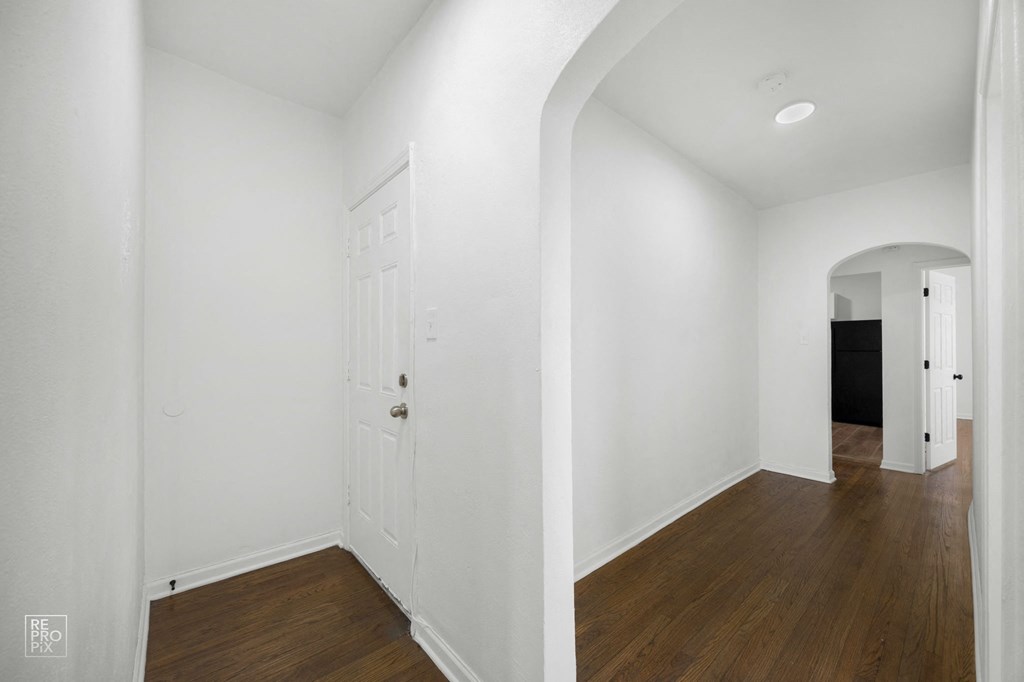 a living room with white walls and wood floors and a white door