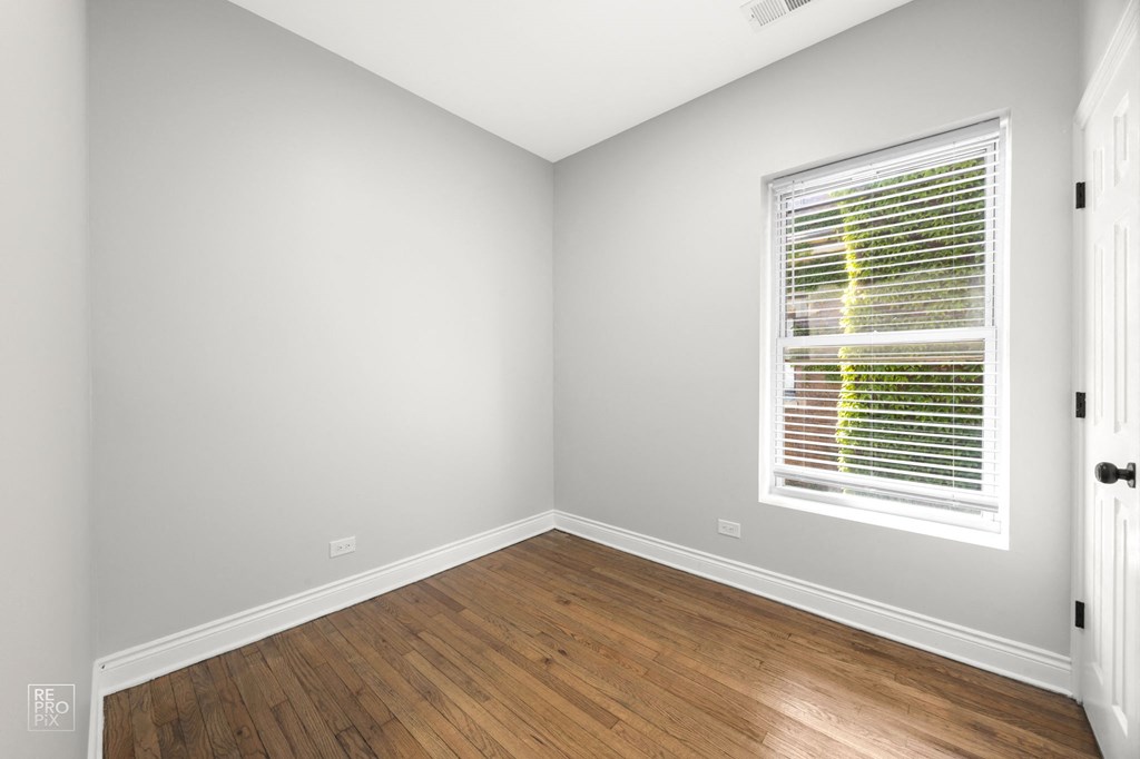 a room with white walls and wood floors and a window