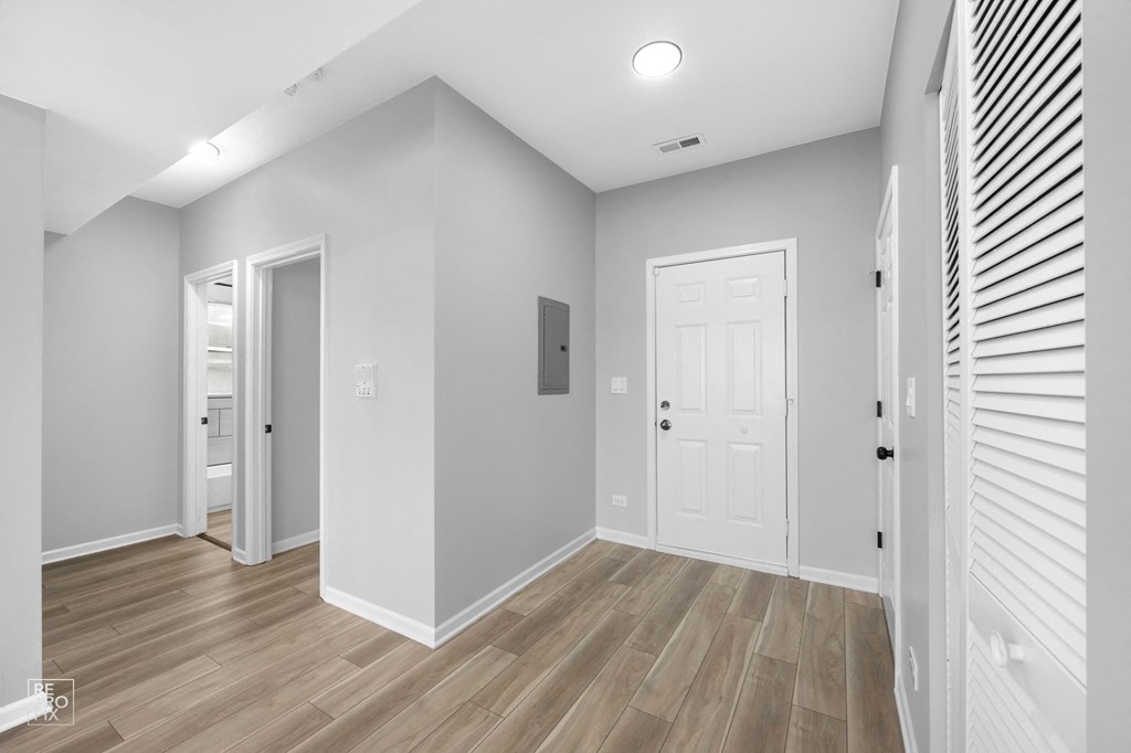 a bedroom with grey walls and a hardwood floor