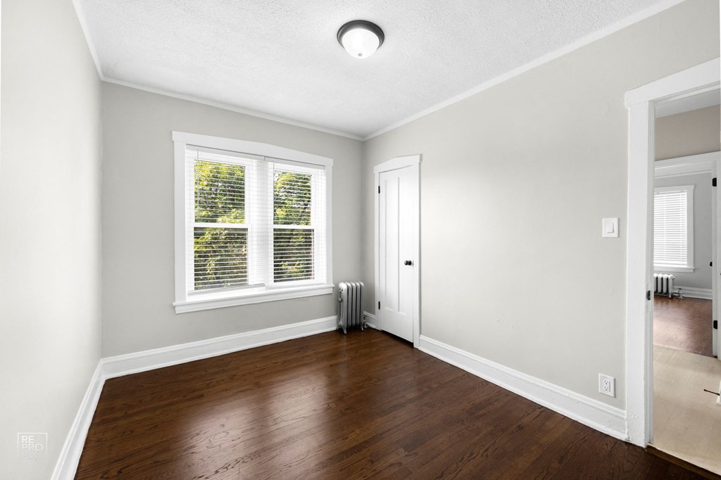 a bedroom with hardwood floors and grey walls