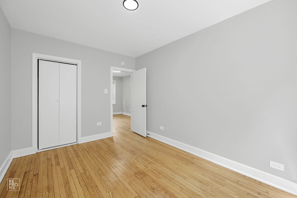 a bedroom with grey walls and hardwood floors