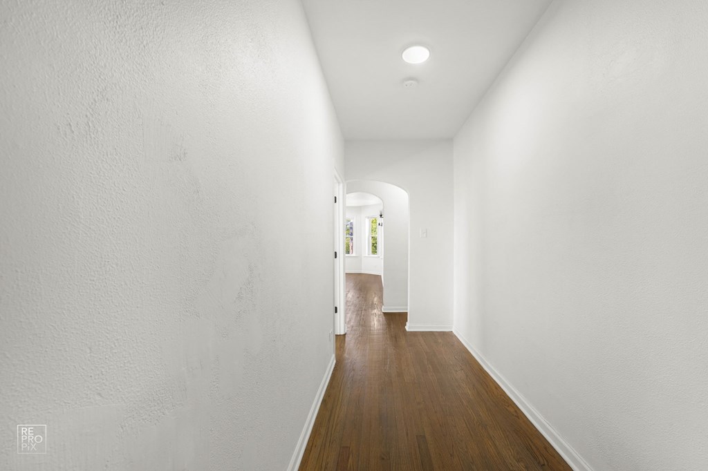 a long hallway with white walls and wood floors