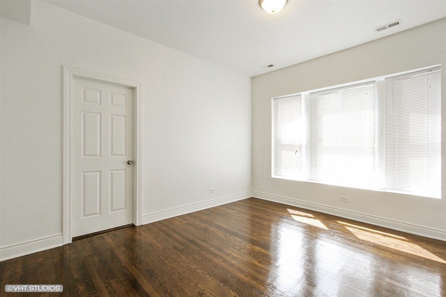 an empty living room with wood floors and a large window