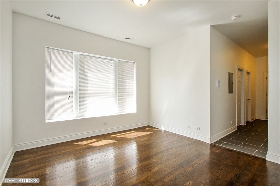 an empty living room with wood floors and a large window