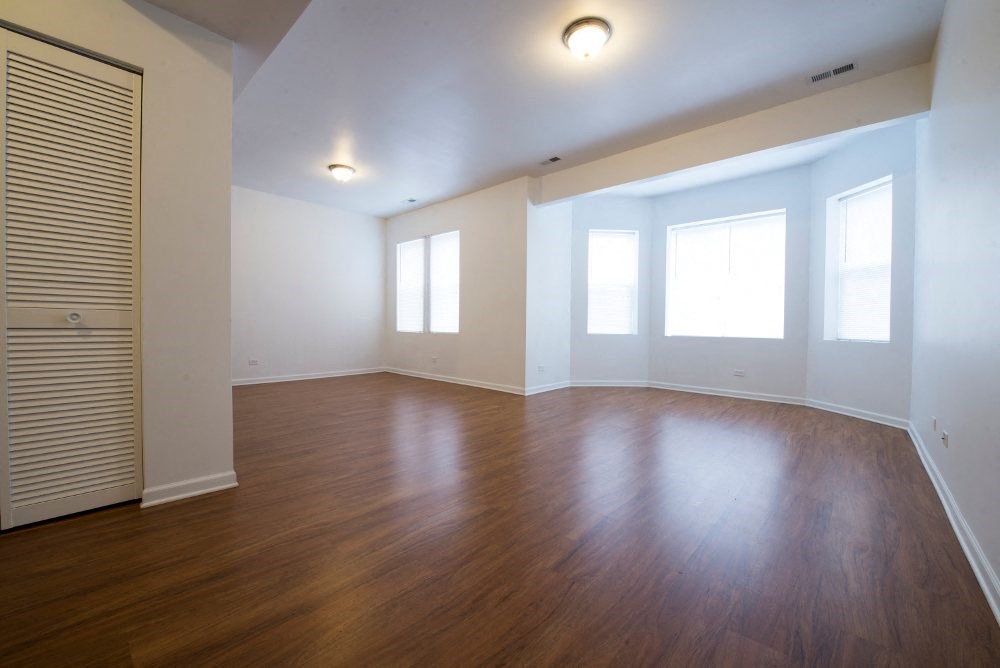an empty living room with wood floors and white walls