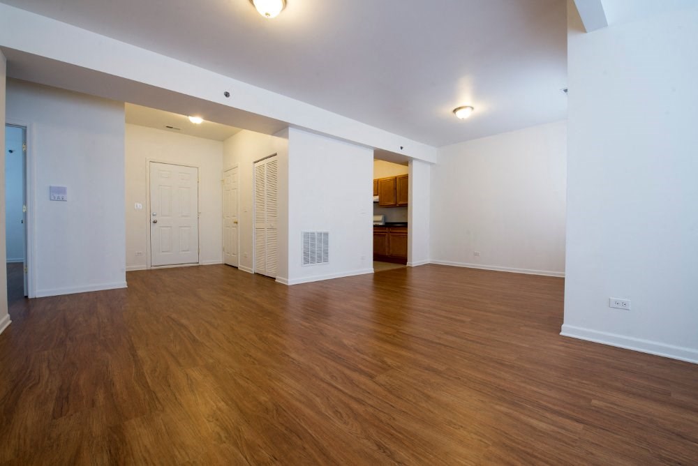 the living room and dining room of an empty apartment with wood floors and white walls