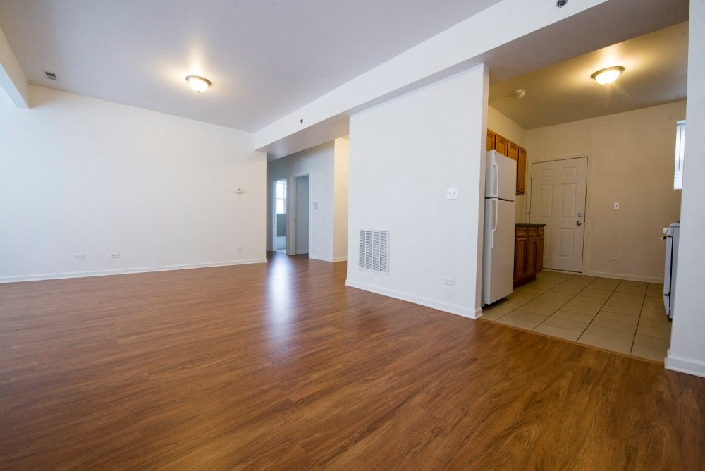 a living room and kitchen with wood floors and white walls