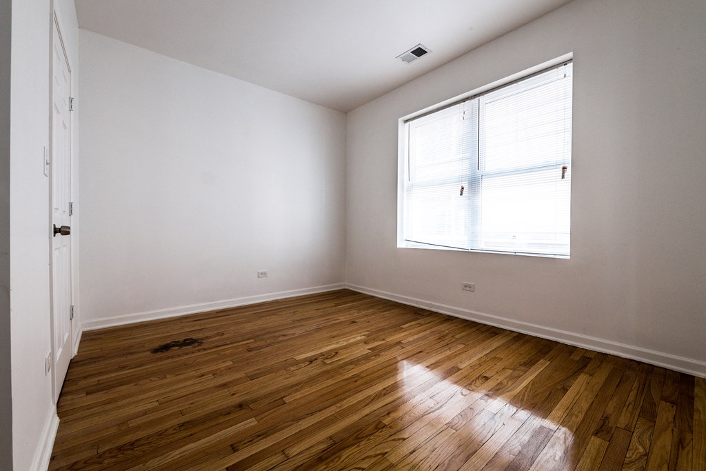 an empty room with wood floors and a window